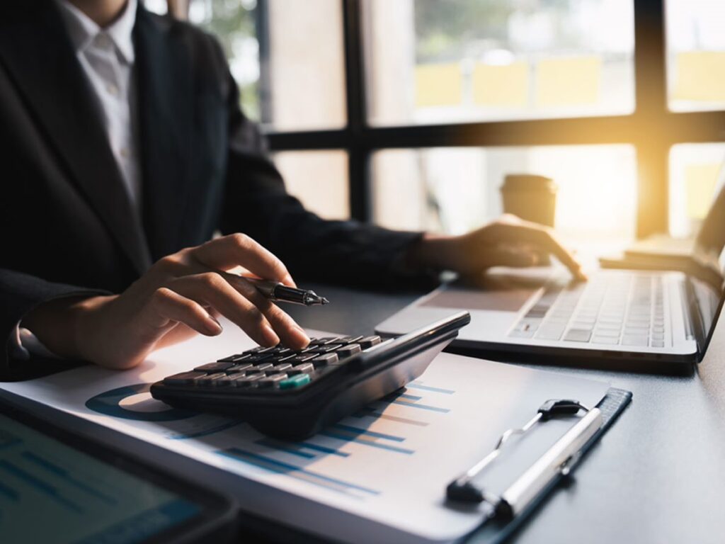 professional worker typing on a laptop and a calculator
