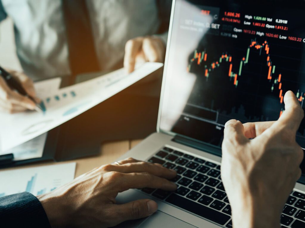 someone looking at a laptop screen with charts on it.